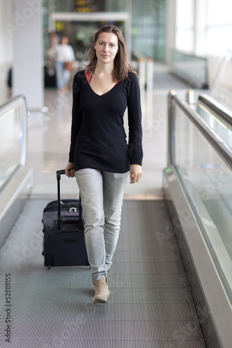 Photo: Frau rollt Koffer am Flughafen Frau rollt Koffer am Flughafen