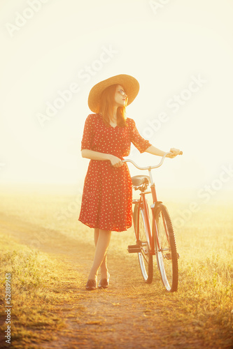 Photo: Girl on a bike in the countryside in sunrise time. Girl on a bike in the countryside in sunrise time.