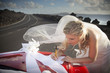 Bride leaning over the hood of the machine, writes a letter.