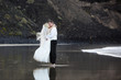 Newlyweds kissing near the ocean shore.
