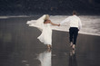 Newlyweds holding hands to go along the ocean shore.