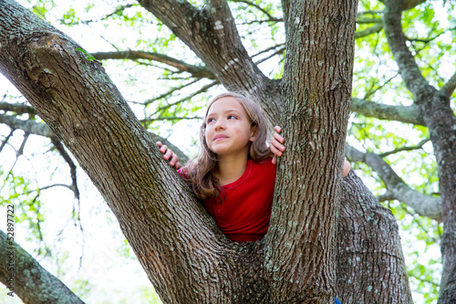 Photo: children kid girl playing climbing to a tree in a park children kid girl playing climbing to a tree in a park