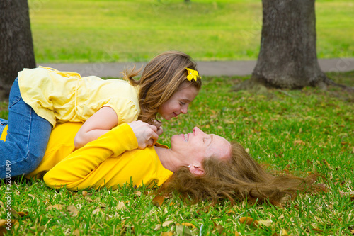 Photo: Daughter and mother playing lying on park lawn Daughter and mother playing lying on park lawn