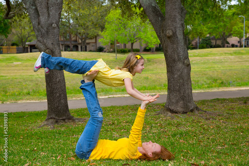 Photo: Daughter and mother playing keep balance lying on park Daughter and mother playing keep balance lying on park