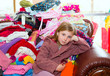 Photo: Blond kid girl sitting on a messy clothes sofa Blond kid girl sitting on a messy clothes sofa