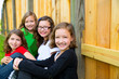 Grils group in a row smiling in a wooden fence
