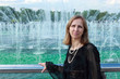 A woman stands near a fountain