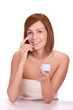 Young girl with natural skin putting cream on face