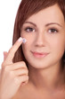 Young girl with natural skin putting cream on face