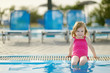 Adorable little girl sitting by a swimming pool
