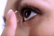 Young woman putting contact lens in her eye close up