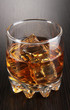 Brandy glass with ice on wooden background