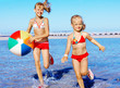 Children holding hands running on  beach.