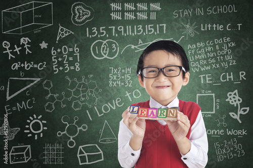 Photo: Cheerful boy student holding LEARN block Cheerful boy student holding LEARN block