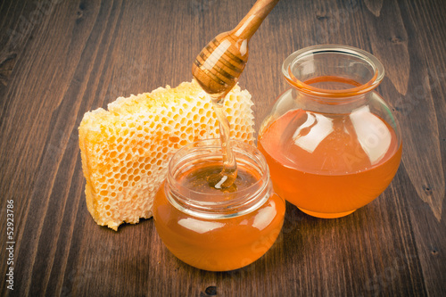 Photo: Honeycomb and honey pot, dipper on wooden table Honeycomb and honey pot, dipper on wooden table