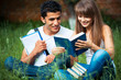 Two students studying in park on grass