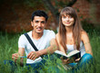 Two students studying in park on grass