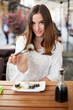 Young woman offering you sushi in a restaurant