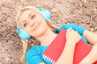 Smiling female lying on a carpet and listening music