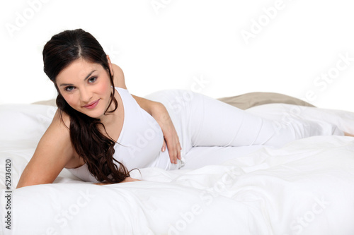 Photo: Cute brown-haired woman lying on a bed Cute brown-haired woman lying on a bed