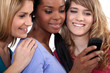 Photo: Three girls reading text message Three girls reading text message