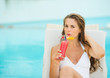 Photo: Young woman laying on chaise-longue and drinking cocktail Young woman laying on chaise-longue and drinking cocktail