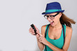 Foto: Funny girl with hat and eyeglasses showing smartphone Funny girl with hat and eyeglasses showing smartphone