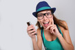Foto: Funny girl with hat and eyeglasses showing smartphone Funny girl with hat and eyeglasses showing smartphone