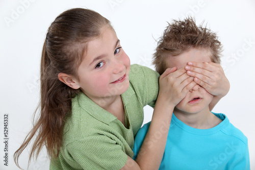 Photo: sister placing hands over brother's eyes sister placing hands over brother's eyes