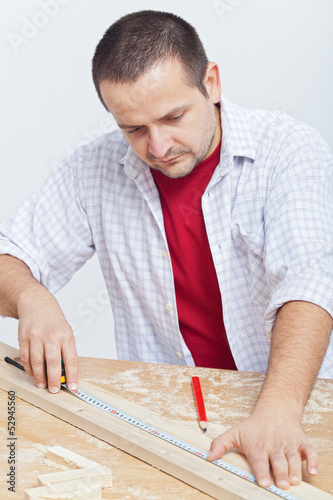 Photo: Woodwork - man measuring wooden planck Woodwork - man measuring wooden planck