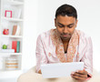 Photo: Indian man using digital tablet pc at home. Indian man using digital tablet pc at home.