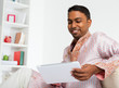 Photo: Indian man using digital tablet at home. Indian man using digital tablet at home.