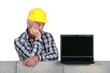 Photo: Confused middle-aged builder looking at laptop Confused middle-aged builder looking at laptop