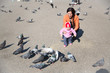 Photo: Child girl and mum playing with doves in the city street Child girl and mum playing with doves in the city street