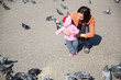 Photo: Child girl and mum playing with doves in the city street Child girl and mum playing with doves in the city street