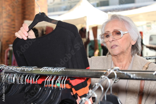 Photo: Woman looking at clothes on a rail Woman looking at clothes on a rail
