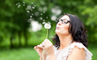 woman blowing on a dandelion