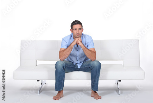 Photo: beautiful young man sitting on the sofa beautiful young man sitting on the sofa