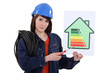 Female electrician holding screwdriver and energy poster