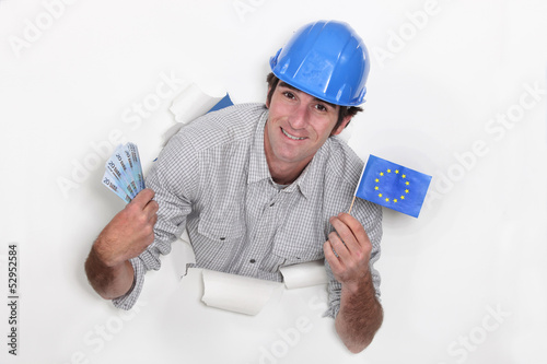 Photo: A male construction worker with cash and a European flag. A male construction worker with cash and a European flag.