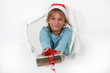 Photo: Little girl in Santa hat offering present Little girl in Santa hat offering present