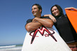 Couple stood on beach with their surfboards