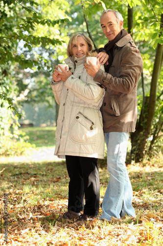 Photo: Couple having a mug of hot chocolate in the forest Couple having a mug of hot chocolate in the forest