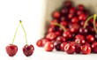 A pair of cherries with spilled cherries in the background