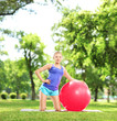 Smiling female athlete with a pilates ball in park