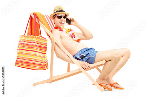 Photo: Man enjoying on a sun lounger while talking on a mobile phone Man enjoying on a sun lounger while talking on a mobile phone