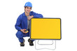 Photo: An electrician kneeled next to a blank road sign. An electrician kneeled next to a blank road sign.