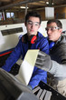 Two factory workers stood by machine