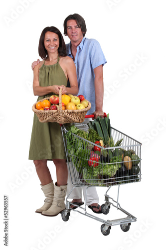 Photo: Couple with a basket and trolley full of fresh produce Couple with a basket and trolley full of fresh produce