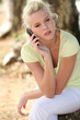 Photo: young woman in the park speaking on her cell phone young woman in the park speaking on her cell phone